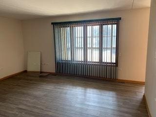 empty room featuring dark wood-style flooring, radiator heating unit, and baseboards