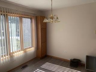 unfurnished room with baseboards, visible vents, a chandelier, and dark wood-type flooring