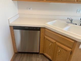 kitchen featuring dishwasher, light countertops, a sink, and brown cabinets