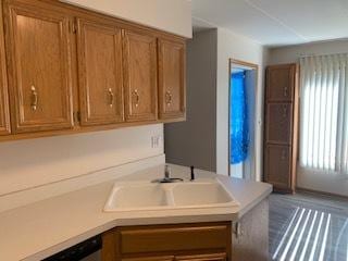 kitchen featuring brown cabinets, light countertops, a sink, and dishwasher