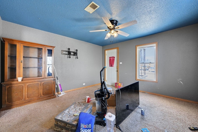 exercise area with a textured ceiling, carpet floors, ceiling fan, and visible vents