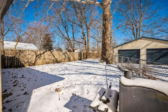 yard covered in snow with a garage, fence, and an outdoor structure