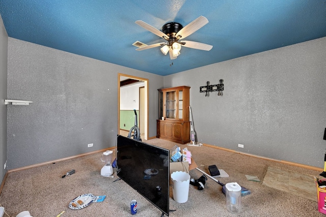 interior space featuring a ceiling fan, visible vents, a textured wall, and carpet flooring