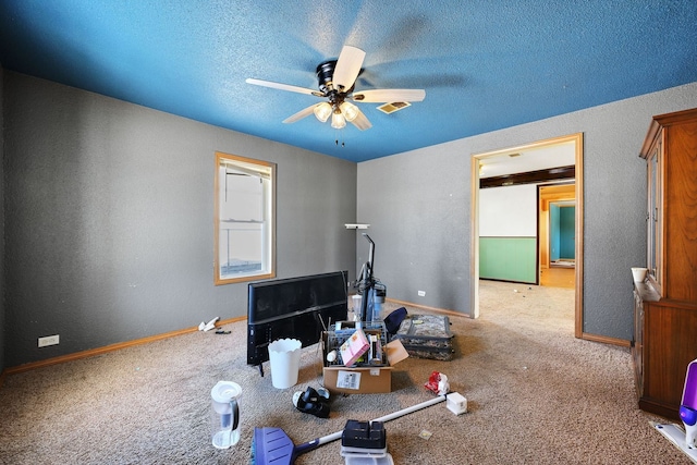 exercise room featuring a textured ceiling, light colored carpet, a ceiling fan, and baseboards