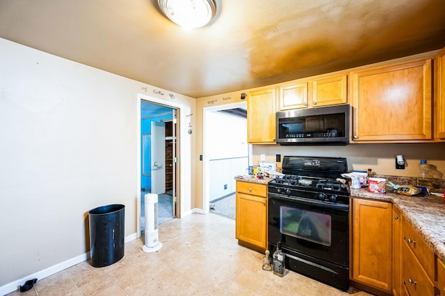 kitchen with black range with gas cooktop, stainless steel microwave, light countertops, and baseboards