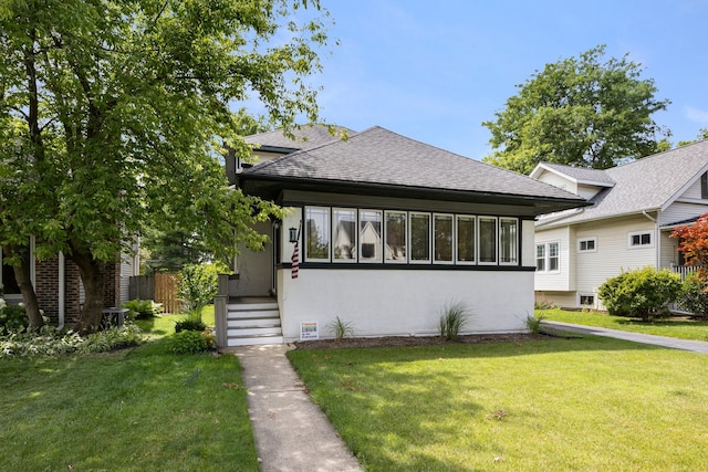 view of front of property featuring a front yard, roof with shingles, fence, and stucco siding