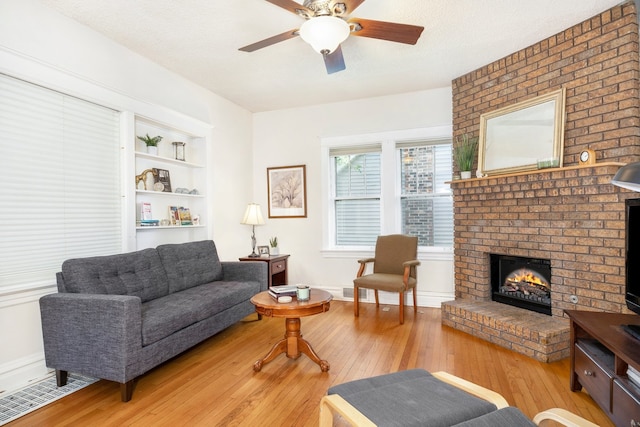 living area featuring light wood-style floors, a brick fireplace, visible vents, and a textured ceiling