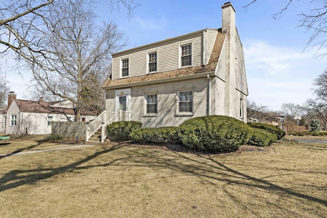 view of front of home featuring brick siding, a chimney, a front lawn, and a shingled roof