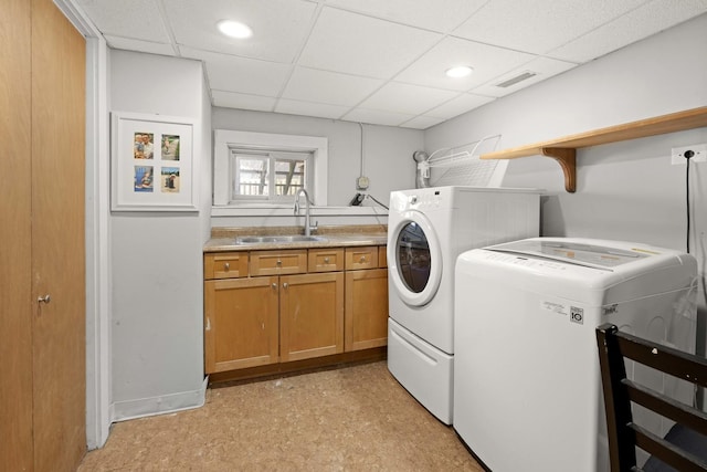 clothes washing area with visible vents, a sink, cabinet space, light floors, and washing machine and clothes dryer