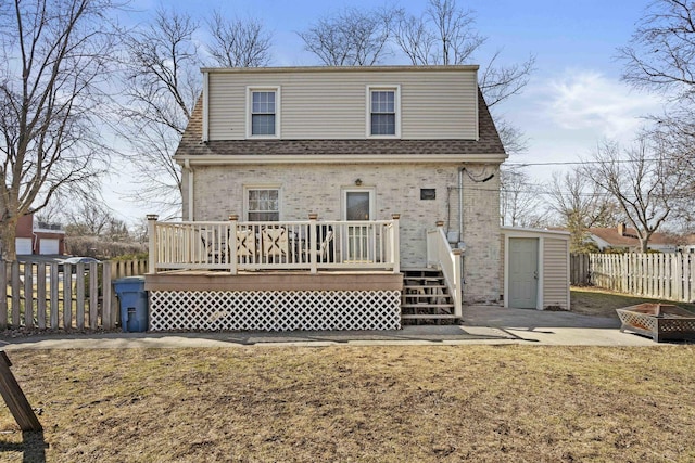 rear view of house with brick siding, roof with shingles, a deck, and fence