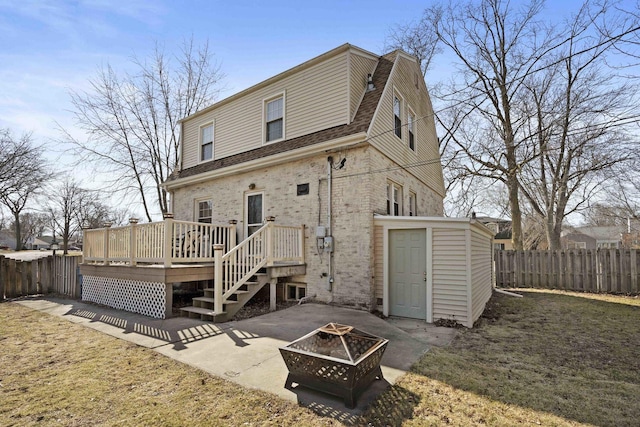 back of property with a deck, a patio, a fenced backyard, an outdoor fire pit, and a shingled roof