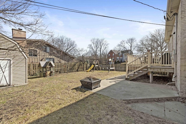 view of yard featuring a playground, a fire pit, a patio, and fence