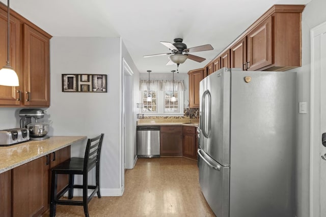 kitchen featuring light stone countertops, brown cabinets, appliances with stainless steel finishes, and ceiling fan