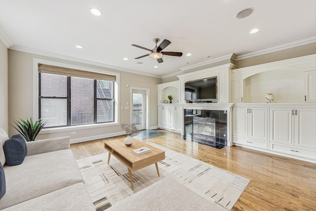 living room with light wood-type flooring, ornamental molding, and a tiled fireplace