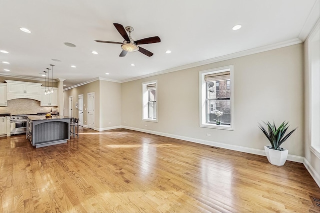 living room featuring a ceiling fan, baseboards, recessed lighting, light wood-style floors, and crown molding