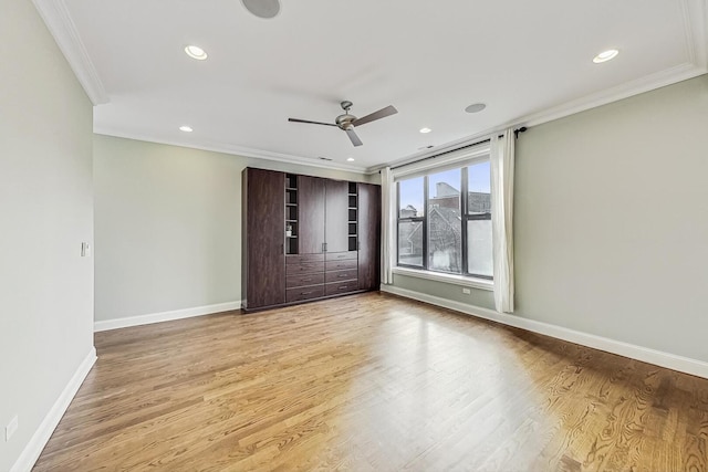 interior space with baseboards, a ceiling fan, light wood-style flooring, and crown molding