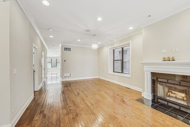 unfurnished living room featuring visible vents, baseboards, and wood finished floors