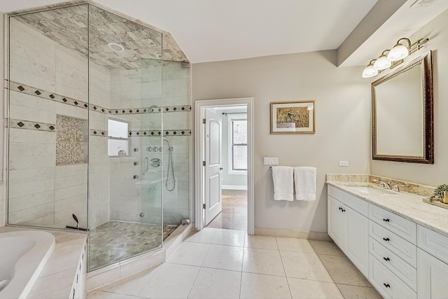 full bathroom with a stall shower, tile patterned flooring, baseboards, a bath, and vanity