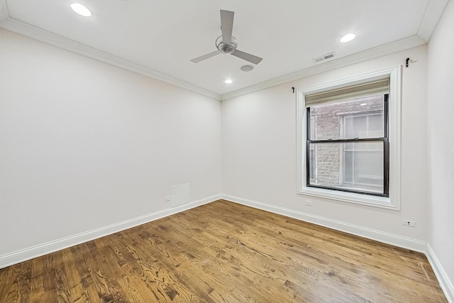 spare room with visible vents, baseboards, wood finished floors, and crown molding