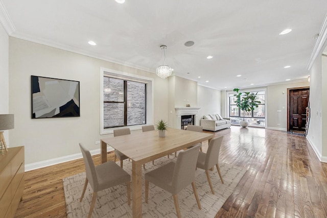 dining area with baseboards, recessed lighting, a fireplace, hardwood / wood-style flooring, and crown molding