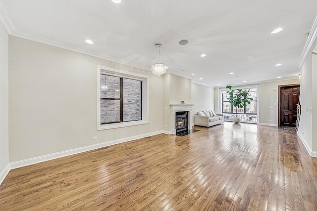 unfurnished living room featuring baseboards, a fireplace with flush hearth, recessed lighting, ornamental molding, and wood-type flooring