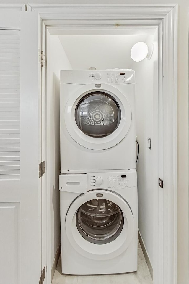 washroom with stacked washer / drying machine, baseboards, and laundry area