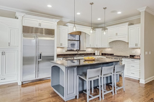 kitchen with white cabinetry, dark countertops, arched walkways, and stainless steel appliances