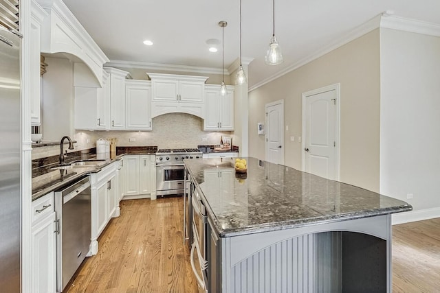 kitchen with backsplash, a kitchen island, appliances with stainless steel finishes, light wood-style floors, and a sink