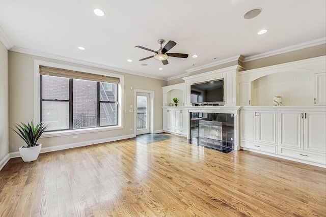 unfurnished living room featuring wood finished floors, recessed lighting, a fireplace, crown molding, and baseboards