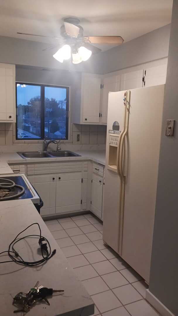 kitchen featuring white cabinetry, light countertops, white refrigerator with ice dispenser, and a sink