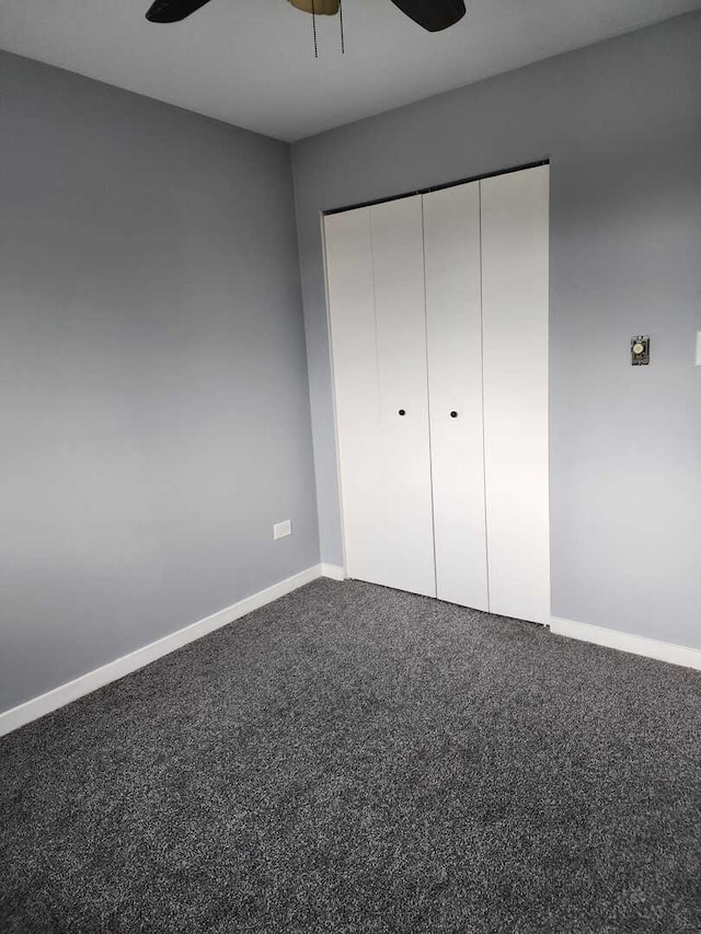 unfurnished bedroom with baseboards, carpet floors, a closet, and a ceiling fan