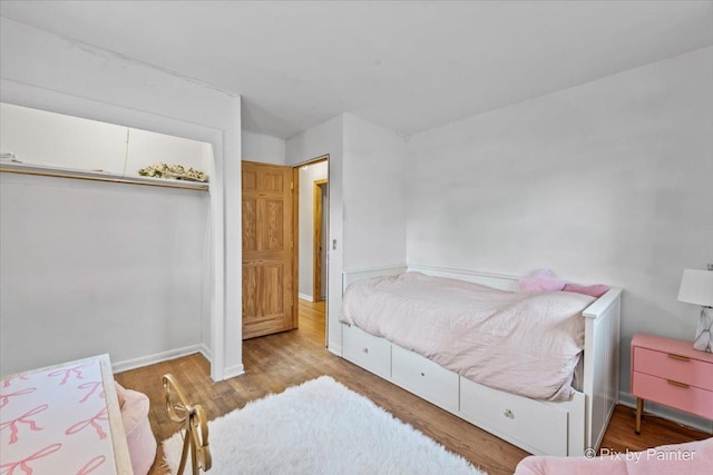 bedroom with a closet, baseboards, and wood finished floors