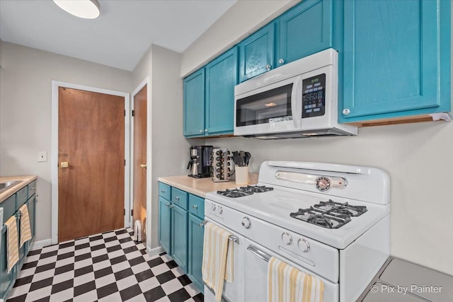 kitchen with dark floors, white appliances, blue cabinetry, and light countertops