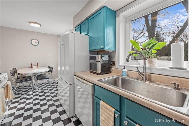 kitchen with white dishwasher, a sink, light countertops, blue cabinetry, and tile patterned floors