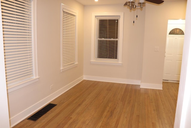 unfurnished room with visible vents, ceiling fan, light wood finished floors, and baseboards