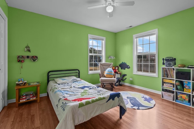 bedroom with ceiling fan, wood finished floors, visible vents, and baseboards
