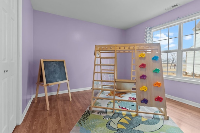 bedroom with wood finished floors, visible vents, and baseboards
