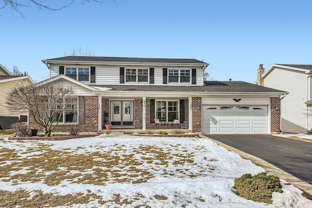 traditional home with aphalt driveway, brick siding, a porch, and an attached garage