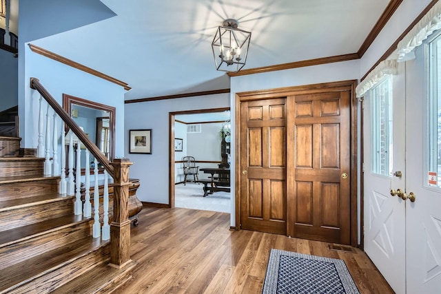 entryway with baseboards, stairway, ornamental molding, wood finished floors, and a notable chandelier