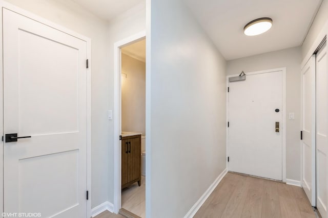 doorway to outside with light wood-style flooring and baseboards