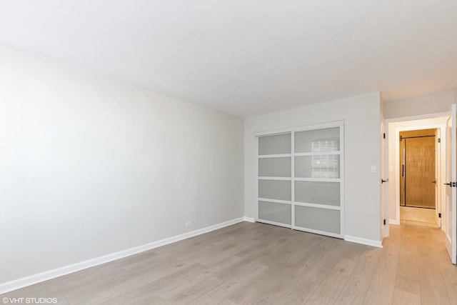 unfurnished bedroom featuring baseboards, a closet, and light wood-style floors