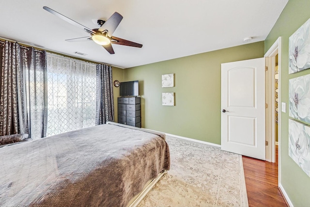 bedroom featuring visible vents, ceiling fan, baseboards, and wood finished floors