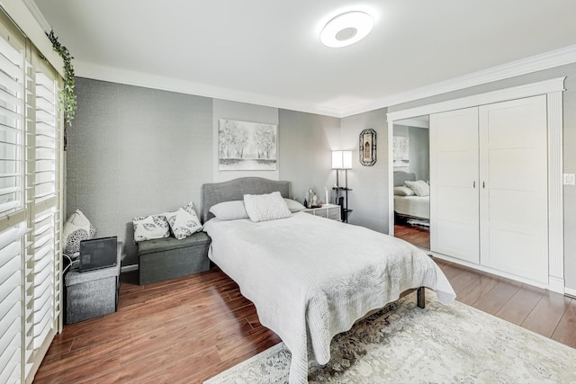 bedroom featuring a closet, dark wood finished floors, and crown molding