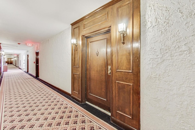 corridor featuring baseboards and a textured wall