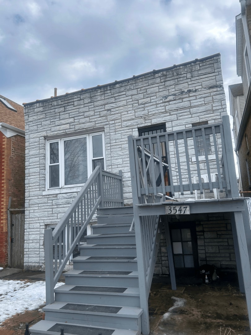 rear view of house with stairway, stone siding, and a wooden deck