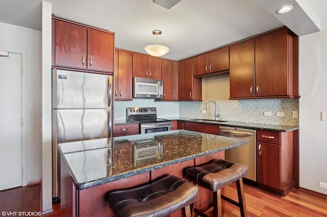 kitchen with decorative backsplash, light wood-style flooring, stainless steel appliances, and a sink