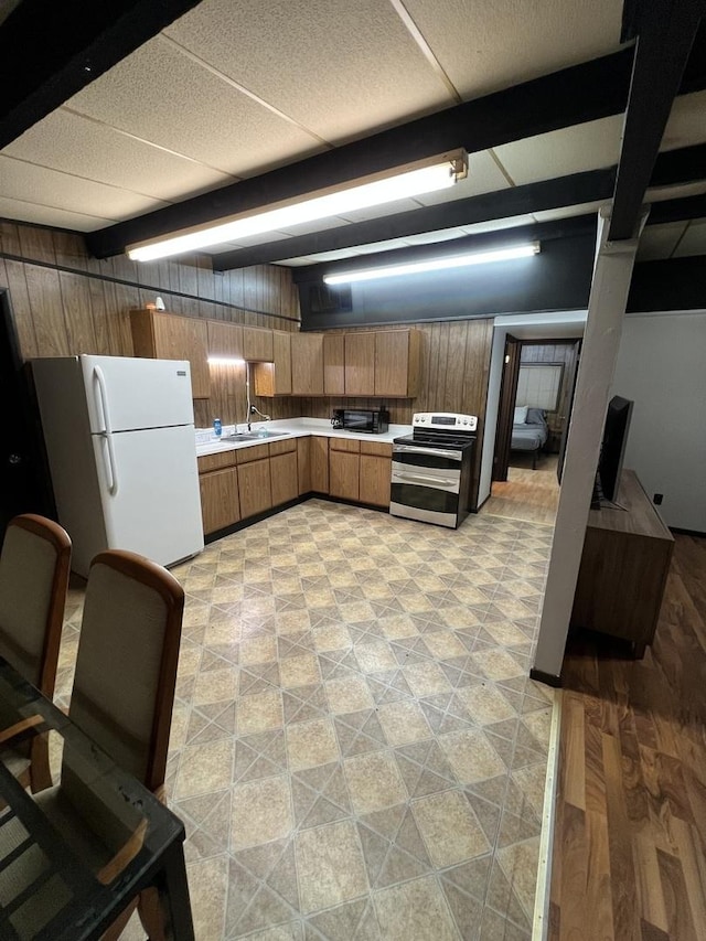 kitchen with light countertops, freestanding refrigerator, brown cabinets, and double oven range