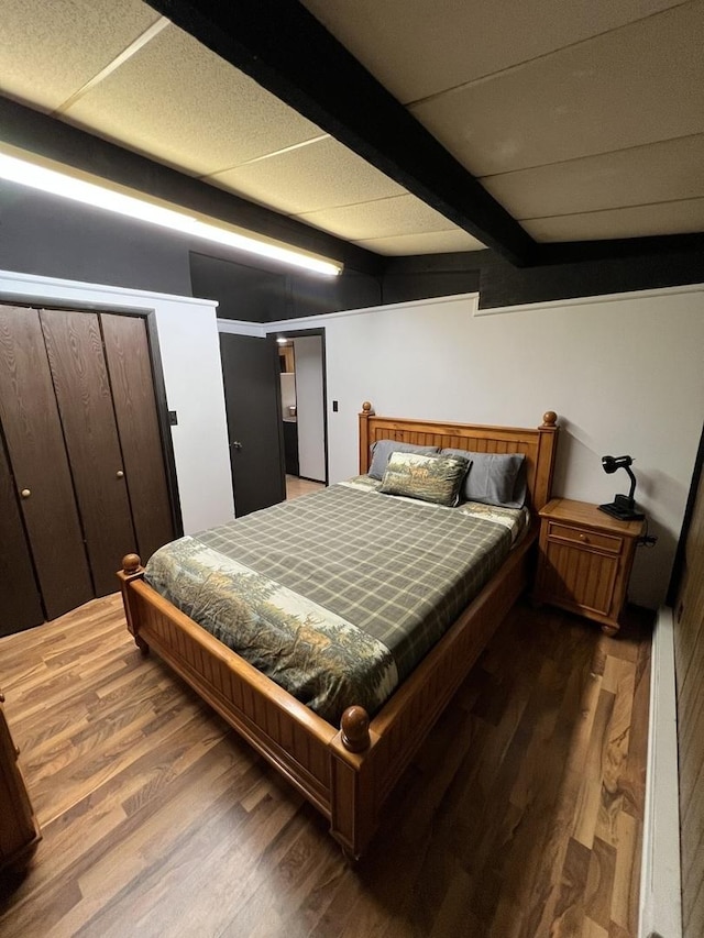 bedroom with beam ceiling and dark wood-type flooring