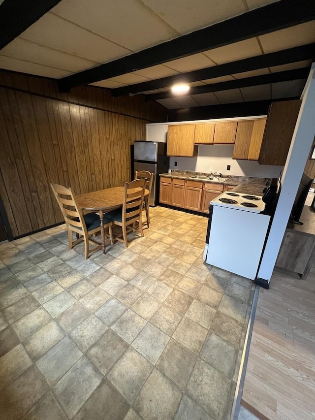 kitchen with white electric range oven, light countertops, freestanding refrigerator, wooden walls, and beamed ceiling