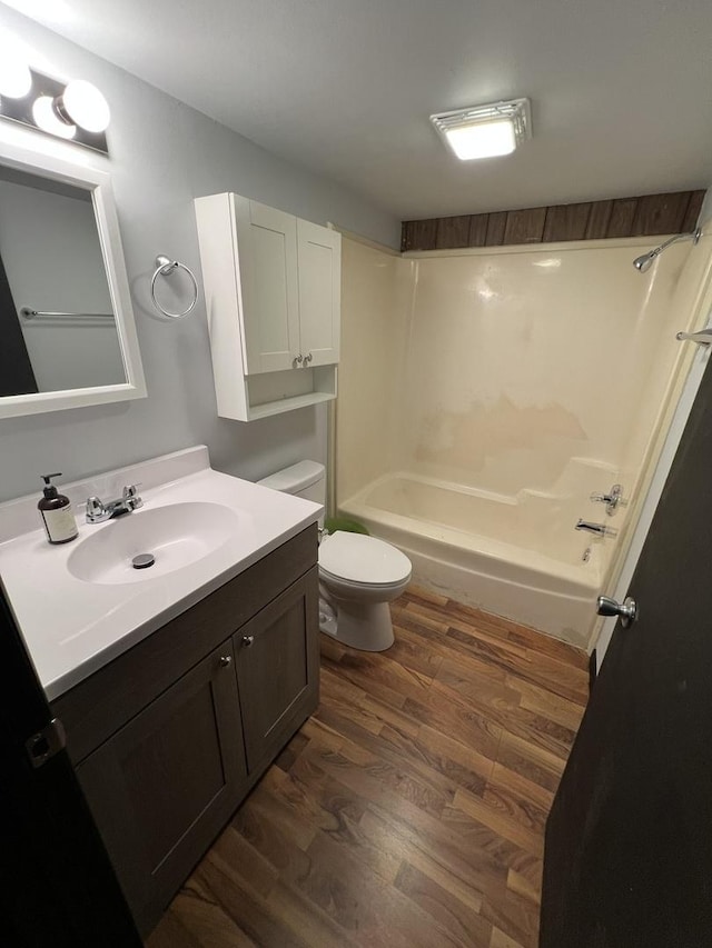 bathroom featuring toilet, vanity, shower / tub combination, and wood finished floors